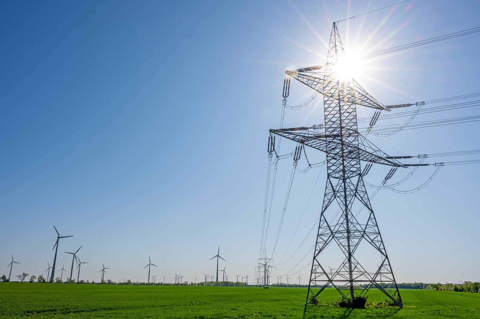 An electricity pylon with the sun behind it